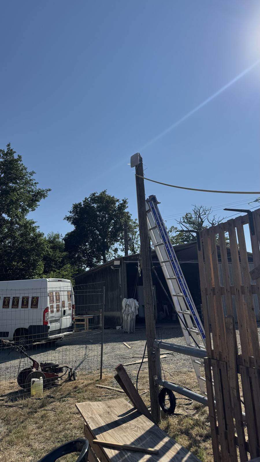 Technicien installant un point d'accès Wi-Fi en haut d'un mât en bois sur le site du festival